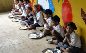 School kids saying prayers before starting with mid-day meal.