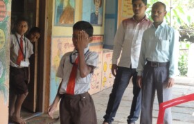 Kid undergoing checkup with one eye at a time. Teachers observe findings